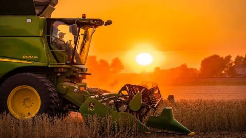 Farm machinery in field at sunset
