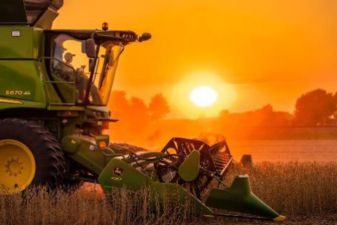 Farm machinery in field at sunset