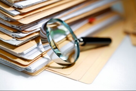 stack of file folders with magnifying glass
