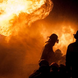 Silhouette of firefighters against a blaze