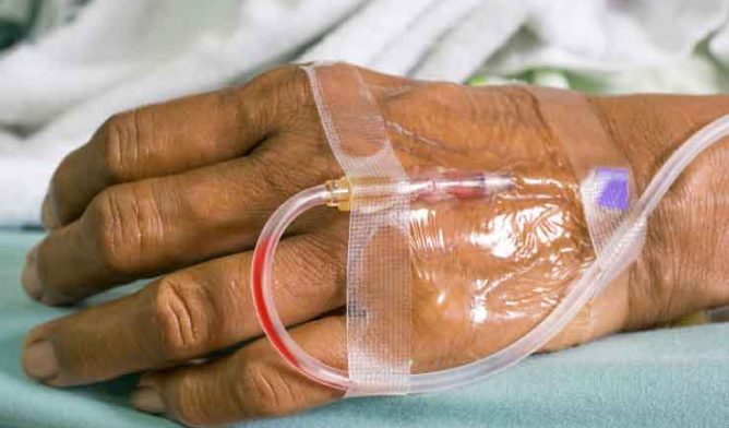 Hand of a old female patient with saline intravenous (IV) drip in
