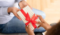 Hands holding gift with red ribbon