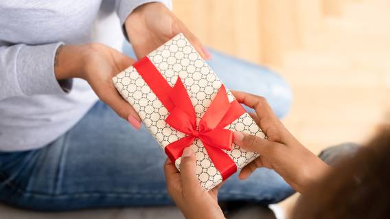 Hands holding gift with red ribbon
