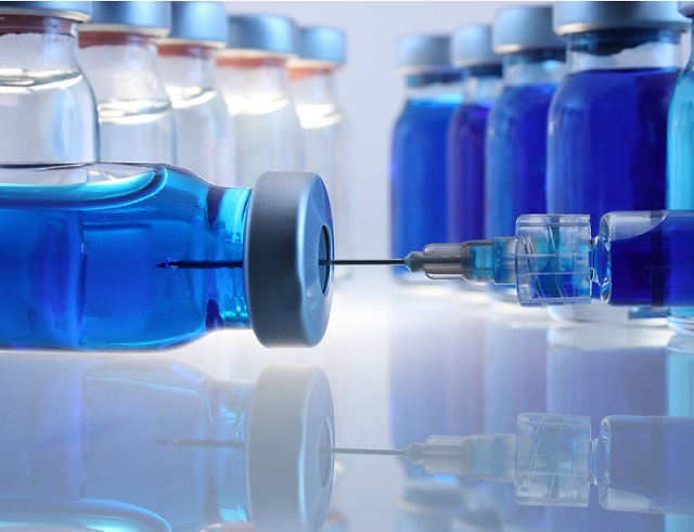 Laboratory bottles with blue content and a syringe