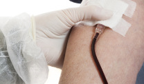A nurse in protective uniform and wearing gloves taking blood sample from an elderly person. Close up.