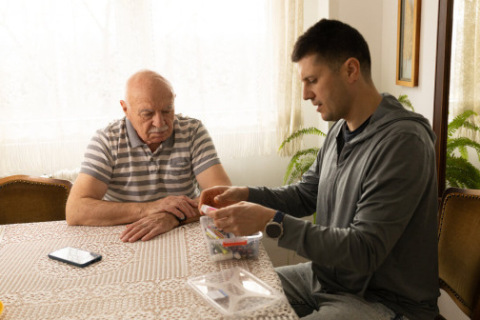 A mesothelioma caregiver helps his father manage his medication.