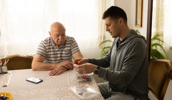 A mesothelioma caregiver helps his father manage his medication.