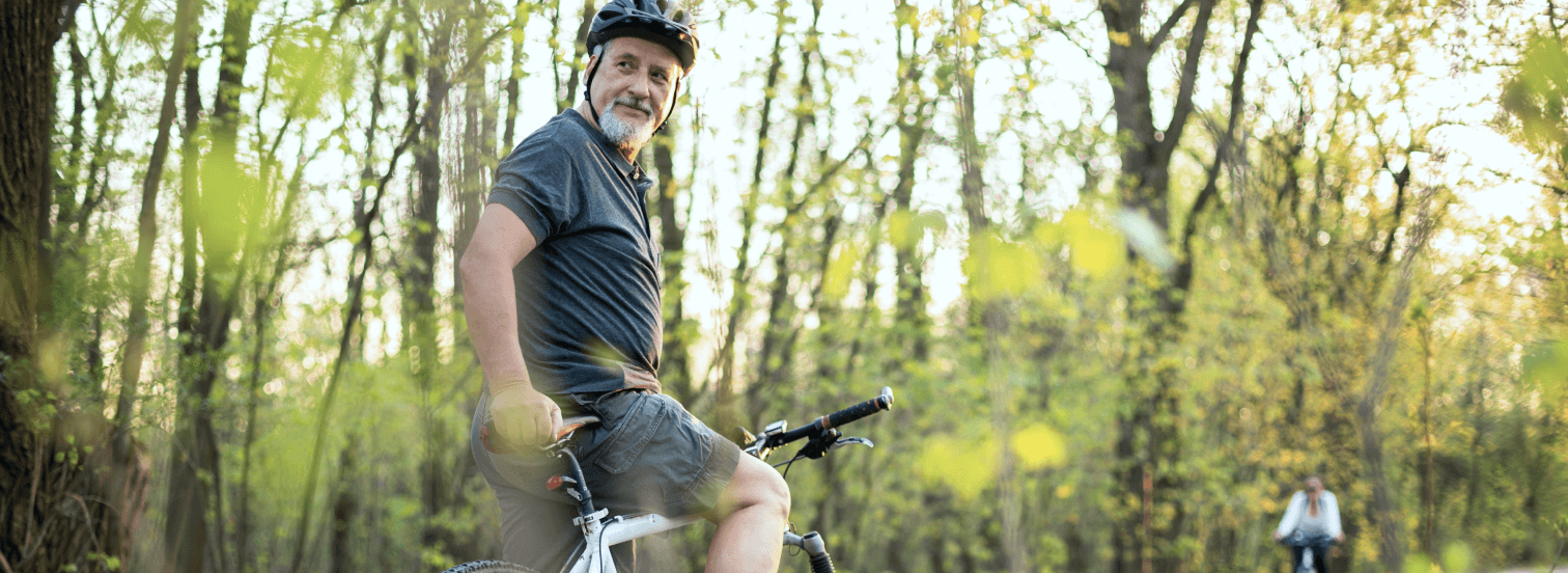 Elderly man enjoys being active by biking through nature