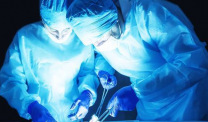 Two surgeons in blue performing surgery