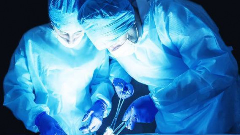 Two surgeons in blue performing surgery