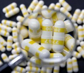 Yellow and white pills under a magnifying glass