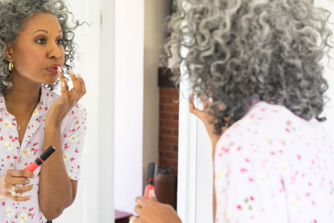 Older woman applying makeup in a mirror