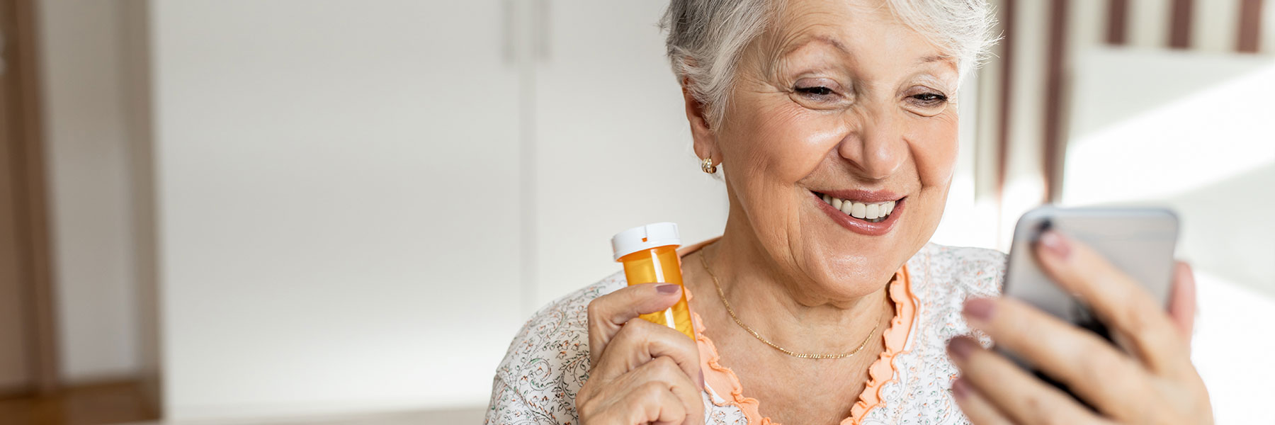 Older woman holding medication while using a phone app