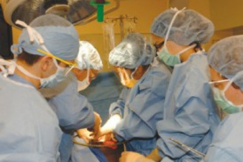 Surgeons with masks and blue scrubs operating on a patient