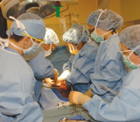 Surgeons with masks and blue scrubs operating on a patient