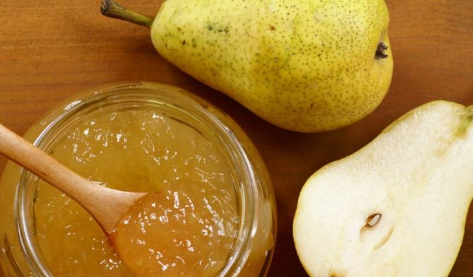 Pear jam with sliced pear on a wooden table