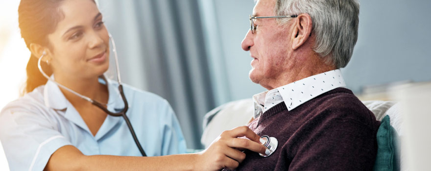 Nurse listening to a elderly man's heart with a stethoscope