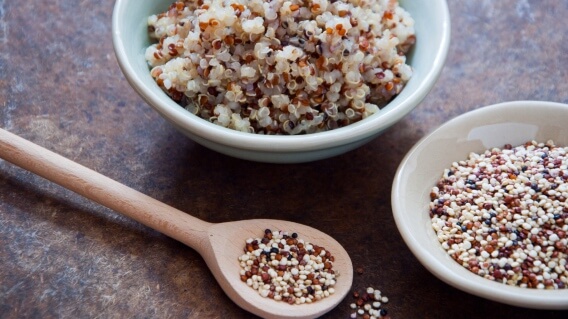 Quinoa in bowls and on a wooden spoon