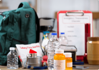 A backpack, flashlight, water bottles, medication and items on a table