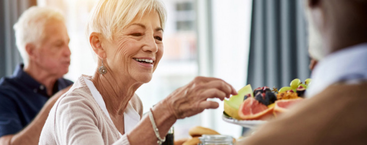 Senior-aged woman eating fruit during an event