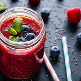 Red smoothie with blueberries and mint in glass