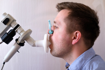 Young man testing breathing function by spirometry