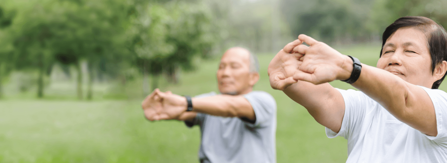 elerly couple stretch in a park