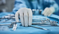 Gloved hands reaching for surgical instruments