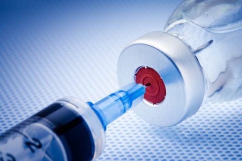 Syringe poking into a vaccine vial