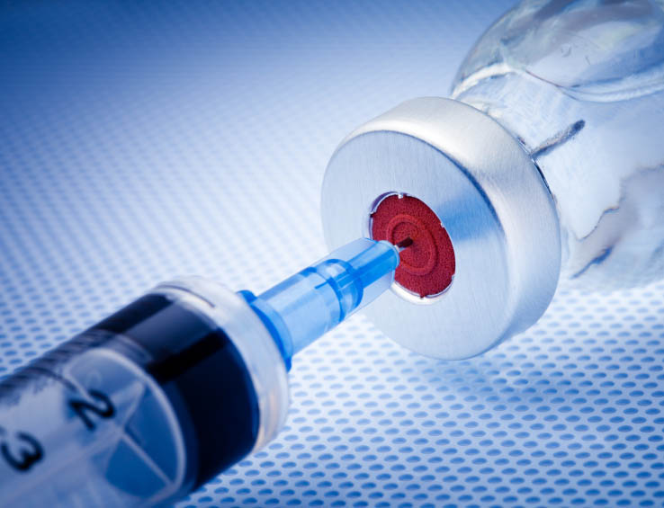 Syringe poking into a vaccine vial