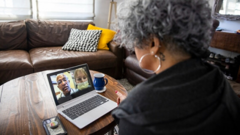 Woman looks at telehealth team on computer