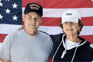 Veteran and spouse in front of U.S.A. flag