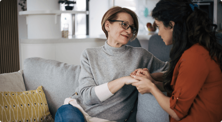 Two women holding hands on a couch