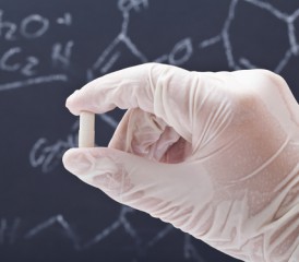 Gloved hand hold a pill in front of a chalkboard Gloved hand hold a pill in front of a chalkboard
