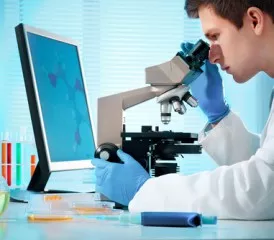 Male researcher looks through a microscope Male researcher looks through a microscope