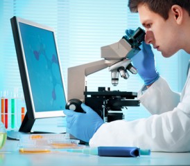 Male researcher looks through a microscope Male researcher looks through a microscope