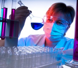 Female researcher examines flask with blue fluid Female researcher examines flask with blue fluid