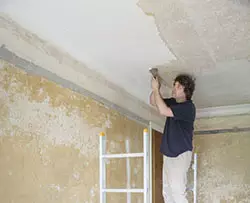 Homeowner scraping popcorn ceiling texture in a house Homeowner scraping popcorn ceiling texture in a house