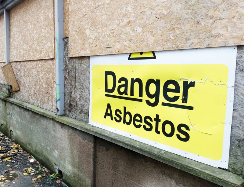 Asbestos warning on boarded up building Asbestos warning on boarded up building