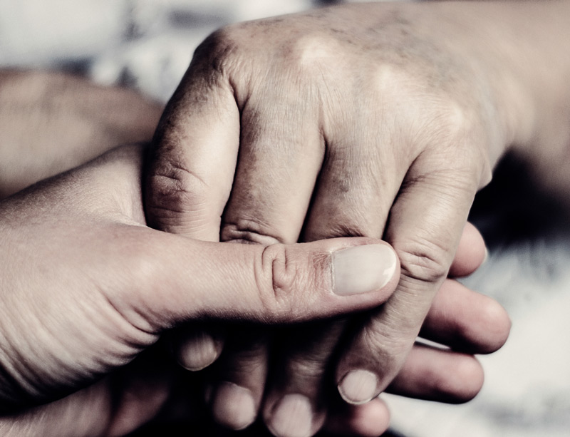 Caregiver holding hand of patient Caregiver holding hand of patient