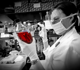 Female researcher holding bottle with red liquid