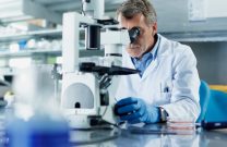 Lab technician using a microscope in a lab