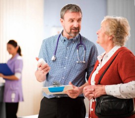 Doctor carrying clipboard talks to patient Doctor carrying clipboard talks to patient