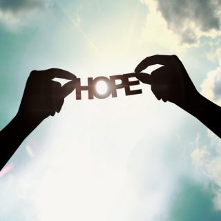 Hands holding paper cut of hope