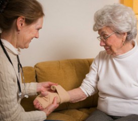 Women bandaging older woman's hand Women bandaging older woman's hand