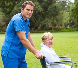 Male Caregiver Pushing Female Patient in Wheelchair Male Caregiver Pushing Female Patient in Wheelchair