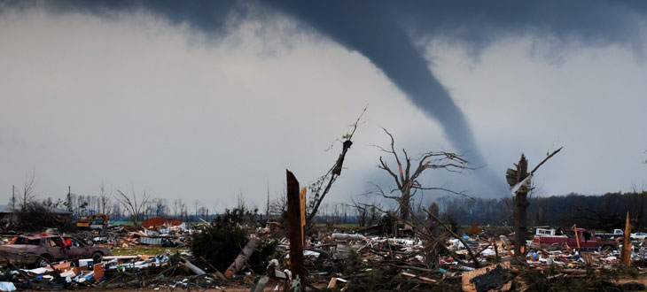 Debris along a road with the tornado shown in the background.