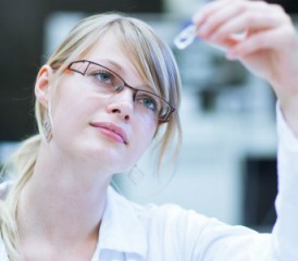 Female researcher looking at vial Female researcher looking at vial