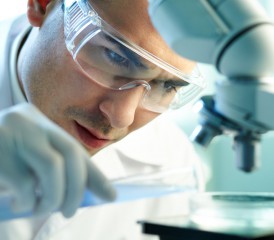 Male researcher examines sample under microscope Male researcher examines sample under microscope