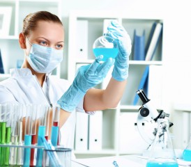 Female researchers examining liquid while wearing a mask over her mouth Female researchers examining liquid while wearing a mask over her mouth